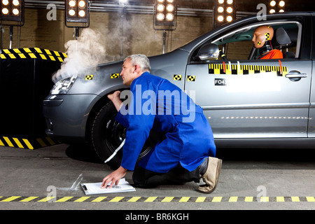 Ein Techniker Prüfung einen Rauchen Crash test Auto mit einem Crashtest-Dummy drin Stockfoto