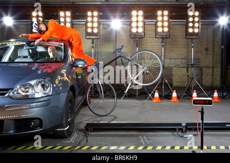 Ein Crashtest-Dummy auf dem Fahrrad stürzt in ein Auto Stockfoto