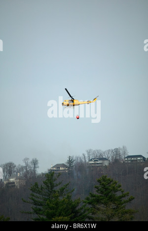 Hubschrauber schleppt einen Eimer mit Wasser zu einen Waldbrand in der Nähe von Arden NC zu kämpfen. Stockfoto