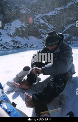 Zanskar Mann Schraubenschlüssel Wasser aus Socken auf zugefrorenen Fluss Indien. Stockfoto