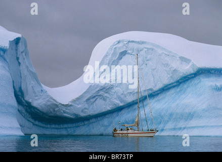 Skip Novak Yacht "Büffelkopf" durch einen massiven verwitterten Eisberg in Bucht von Fournier, antarktische Halbinsel. Stockfoto