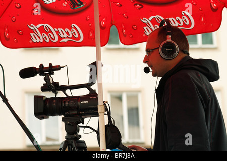 Mann mit Kopfhörer Videoaufnahmen unter Coca-Cola (Coke) Dach auf der Straße. Prag, Tschechische Republik, August 2010 Stockfoto