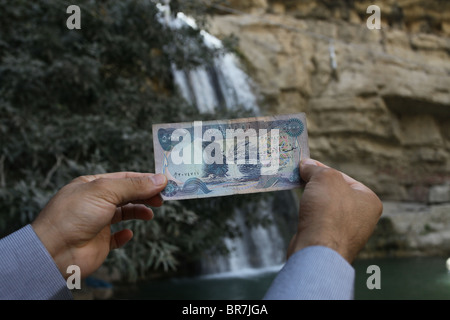 Ein Mann hält einen 5,000-irakischen Dinar am Wasserfall von Geli Ali Beg, der in der Banknote Kurdistan Nordirak abgebildet ist Stockfoto