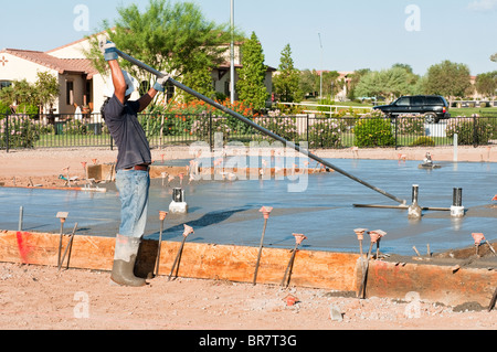 Ein Bauarbeiter endet eine neu gegossene Betonplatte mit einem Schwimmer Werkzeug. Stockfoto