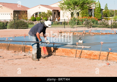 Ein Bauarbeiter endet eine neu gegossene Betonplatte mit einem Schwimmer Werkzeug. Stockfoto