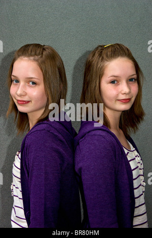 Identische Teenager weibliche Zwillinge gekleidet gleichermaßen in derselben Kleidung Outfits Frisuren Stockfoto