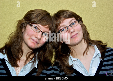 Identische weibliche Teenager Zwillinge gekleidet gleichermaßen in derselben Kleidung Outfits Frisuren Stockfoto