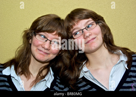 Identische weibliche Teenager Zwillinge gekleidet gleichermaßen in derselben Kleidung Outfits Frisuren Stockfoto