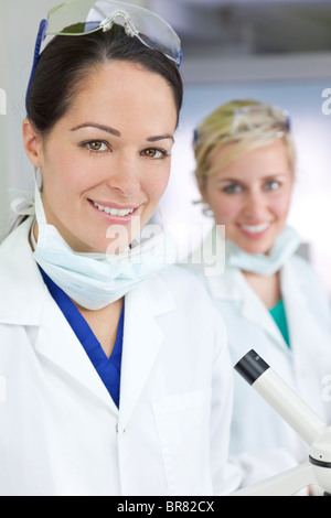 Zwei attraktive lächelnd Wissenschaftlerinnen oder Ärztinnen trägt einen weißen Kittel in einem Labor oder Krankenhaus Stockfoto