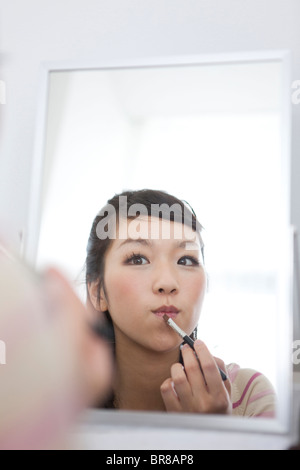 Junge Frau Auftragen von Lippenstift Stockfoto
