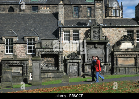Ein paar zu Fuß durch 17. Jahrhundert Wandbild Denkmäler in Greyfriars Kirkyard in Edinburgh, Schottland. Stockfoto