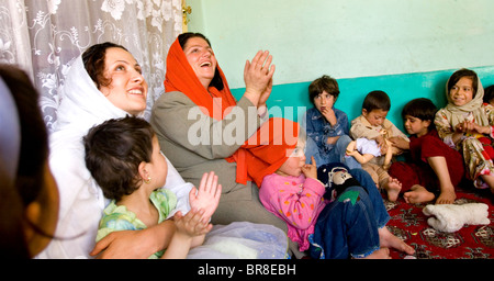 Ein Lehrer führt Kinder in Gesang und klatschten an einer Vorschule in Kabul. Stockfoto