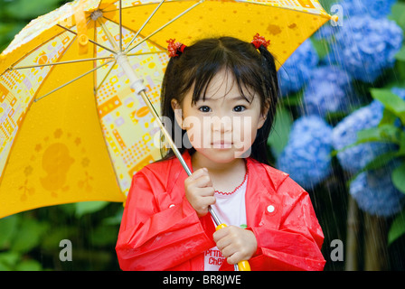 Mädchen unter dem Dach im Regen Stockfoto