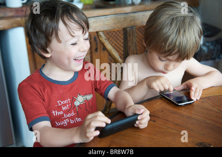 kleine Kinder spielen mit Iphones auf Urlaub in Ibiza Spanien Stockfoto