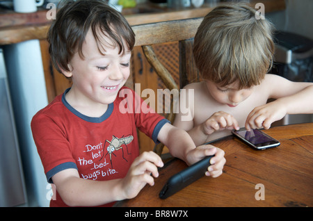 kleine Kinder spielen mit Iphones auf Urlaub in Ibiza Spanien Stockfoto