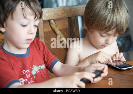 kleine Kinder spielen mit Iphones auf Urlaub in Ibiza Spanien Stockfoto