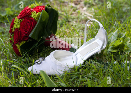 Hochzeit-Symbole in den Rasen. Ringe, Brautstrauß und weißen high Heel Schuh. Stockfoto