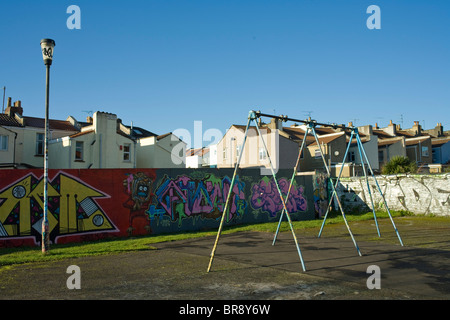 Kinder Schaukeln auf Spielplatz mit graffiti Stockfoto