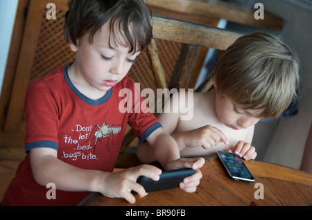 kleine Kinder spielen mit Iphones auf Urlaub in Ibiza Spanien Stockfoto