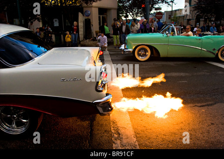 Zuschauer stehen entlang einer Straße, die gerade eines Oldtimers mit einem flammenden Auspuff in Coeur d ' Alene, Idaho. Stockfoto