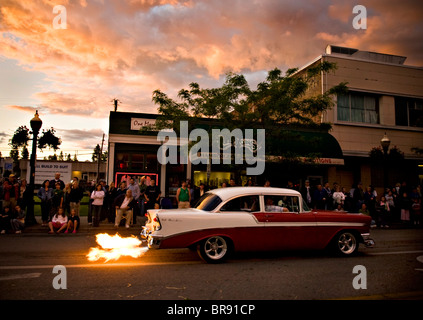 Zuschauer stehen entlang einer Straße, die gerade eines Oldtimers mit einem flammenden Auspuff in Coeur d ' Alene, Idaho. Stockfoto