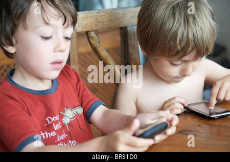 kleine Kinder spielen mit Iphones auf Urlaub in Ibiza Spanien Stockfoto