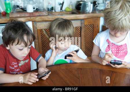 kleine Kinder spielen mit Iphones auf Urlaub in Ibiza Spanien Stockfoto