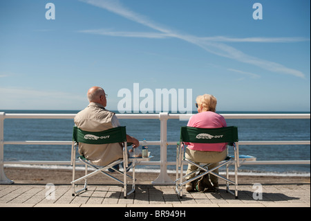 Rückansicht des ein älteres Ehepaar sitzt auf Aberystwyth Promenade an einem sonnigen Nachmittag, Wales UK Stockfoto