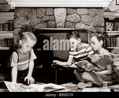 1950ER JAHREN KINDER SPIELEN SCHALLPLATTEN UND BÜCHER ZU LESEN KAMIN Stockfoto