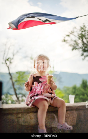 ein kleines Mädchen lacht beim Eis essen, im Staat New York Stockfoto