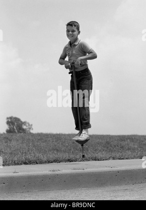 1960ER JAHRE JUNGE SPRINGT AUF POGO STICK Stockfoto