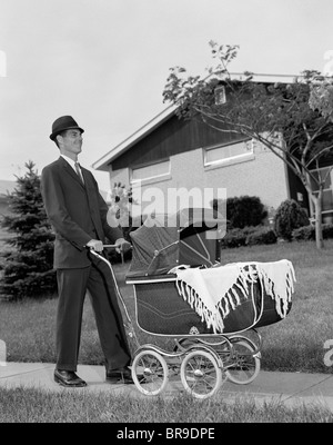 1960ER JAHRE MANN SCHIEBEN KINDERWAGEN KINDERWAGEN SUBURBAN BÜRGERSTEIG Stockfoto