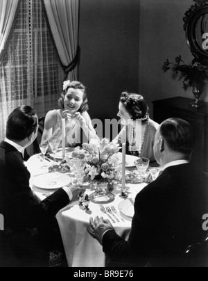 1930ER JAHREN ZWEI PAARE FÖRMLICHEN DINNER-PARTY, DIE AM TISCH SITZEN Stockfoto