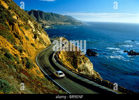 1990ER JAHREN WEIßEN KLEINWAGEN FAHREN ENTLANG DER KÜSTENSTRASSE ZWISCHEN HOHEN FELSEN UND DEN OZEAN BIG SUR CALIFORNIA USA Stockfoto