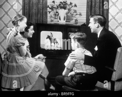 1950ER JAHREN VIERKÖPFIGE FAMILIE GERADE SCHWARZ / WEIß-TV-PROGRAMM VON EINEM COWBOY AUF EINEM PFERD Stockfoto