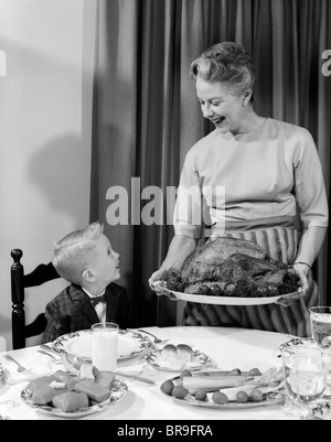 1960ER JAHREN GROßMUTTER ENKEL GEBRATENEM TRUTHAHN THANKSGIVING-DINNER Stockfoto