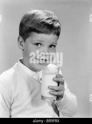 1960ER JAHREN LÄCHELNDE JUNGE HOLDING GLAS MILCH BLICK IN DIE KAMERA Stockfoto