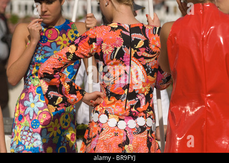 1970er Jahre Retro-Styles drei junge Frauen beim Goodwood Festival of Speed. Mädchen in leuchtenden Retro-Kleidern und eines in einem roten Plastikkleid Goodwood Sussex 2010s 2010 UK. HOMER SYKES Stockfoto