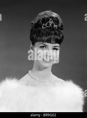 1960ER JAHRE HÜBSCHE JUNGE FRAU TRÄGT TIARA PELZ GESTOHLEN UND EINE ZEICHENFOLGE VON PERLEN BLICK IN DIE KAMERA Stockfoto