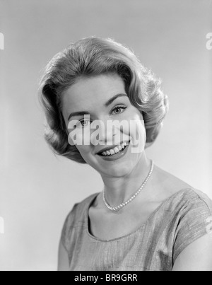 1950S 1960S PORTRAIT BLONDE FRAU MIT PERLENKETTE, BLICK IN DIE KAMERA LÄCHELN Stockfoto