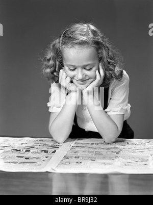 1940ER JAHRE KIND LESEN ZEITUNG COMICS LÄCHELND Stockfoto