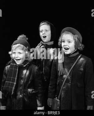 1940ER JAHREN DREI KINDER SINGEN CAROLING Stockfoto