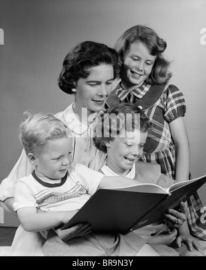 LESEBUCH DER 1950ER JAHRE MUTTER MIT DREI KINDERN Stockfoto