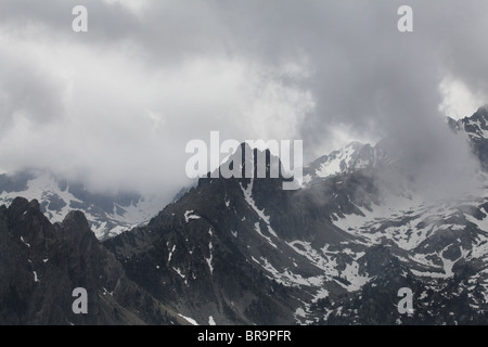 Steigender Nebel niedrigen Wolken wirbelt um Els Encantats Höhepunkt von d'Amitges in Sant Maurici Nationalpark Pyrenäen Spanien gesehen Stockfoto