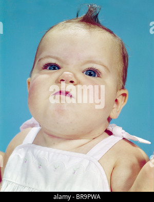 1960ER JAHRE BABY PORTRAIT MACHEN LUSTIGE MIMIK, BLICK IN DIE KAMERA Stockfoto