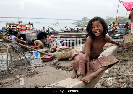 Ein junges Mädchen lächelt, als sie sitzt auf einem Holzboot in der Nähe ein Hausbesetzer Slum in Kampong Cham, Kambodscha. Stockfoto