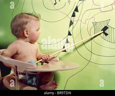 1960ER JAHRE BABY IM HOCHSTUHL MIT HÖLZERNEN ZEIGER AUF TIEFDRUCKGEBIET AUF WETTERKARTE ZEIGEN Stockfoto