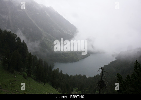 Steigender Nebel und niedrige Wolken Wirbeln über Sant Maurici See auf Pyrenäen Traverse und Nationalpark Pyrenäen Spanien Stockfoto