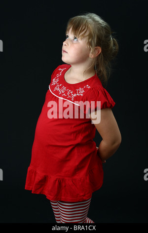 Schuldig kleines Mädchen blickte mit Händen hinter ihrem Rücken auf schwarz Stockfoto