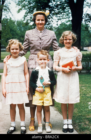 1950ER JAHREN MUTTER UND DREI KINDER VERKLEIDET POSIERT FÜR FOTOS IM FREIEN Stockfoto